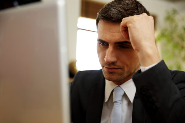 Pensive businessman using laptop at office